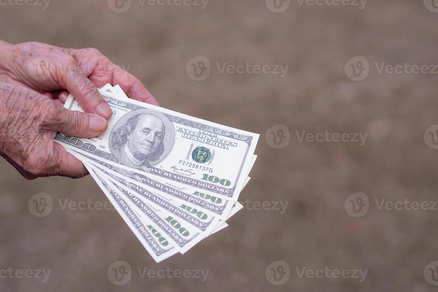 Close-up of elderly woman hands holding 100 dollar amount of 500 dollars. photo