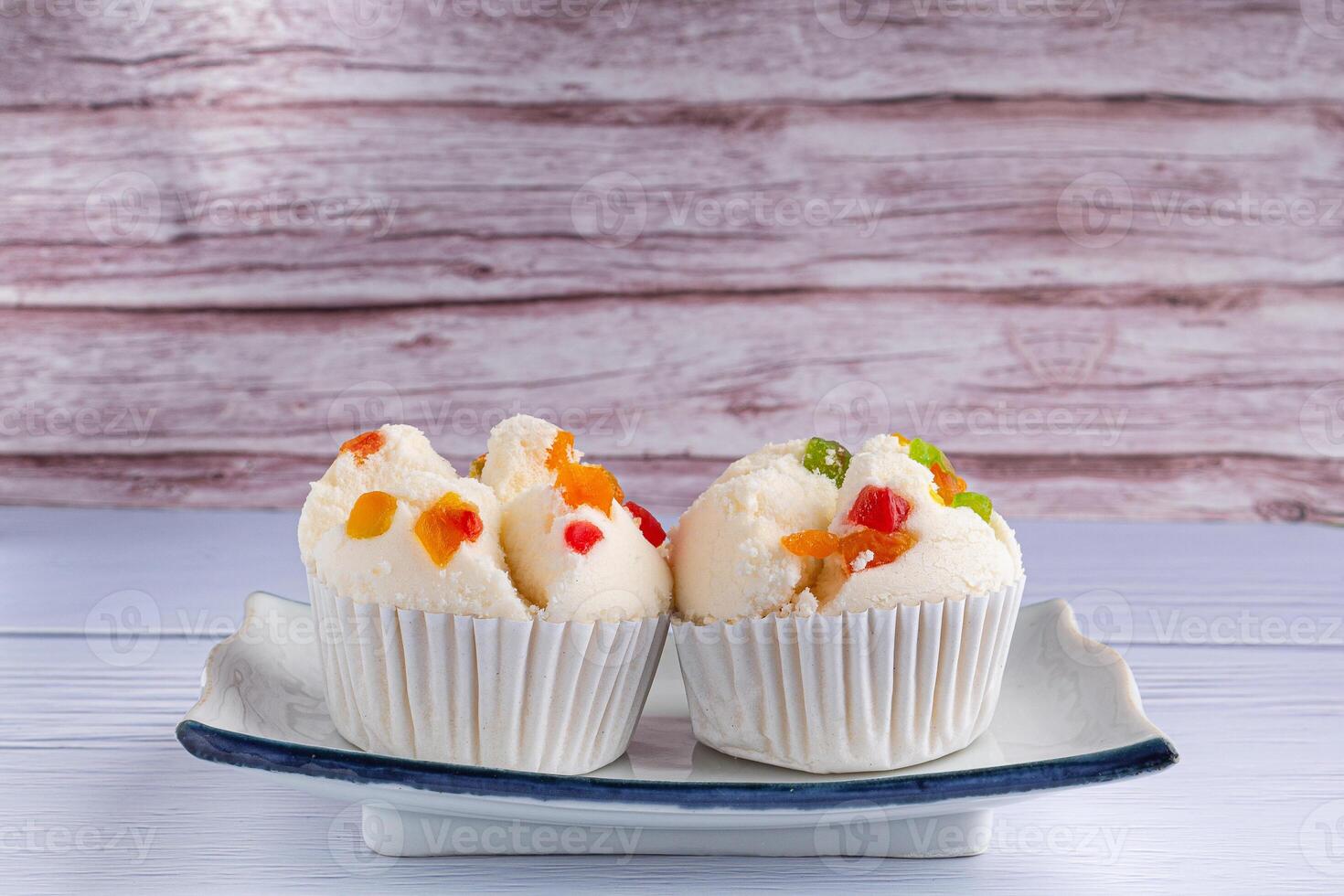 Side view of Thai steamed cupcakes topped with dry fruit on a plate on a blue cloth with a wooden background.. photo