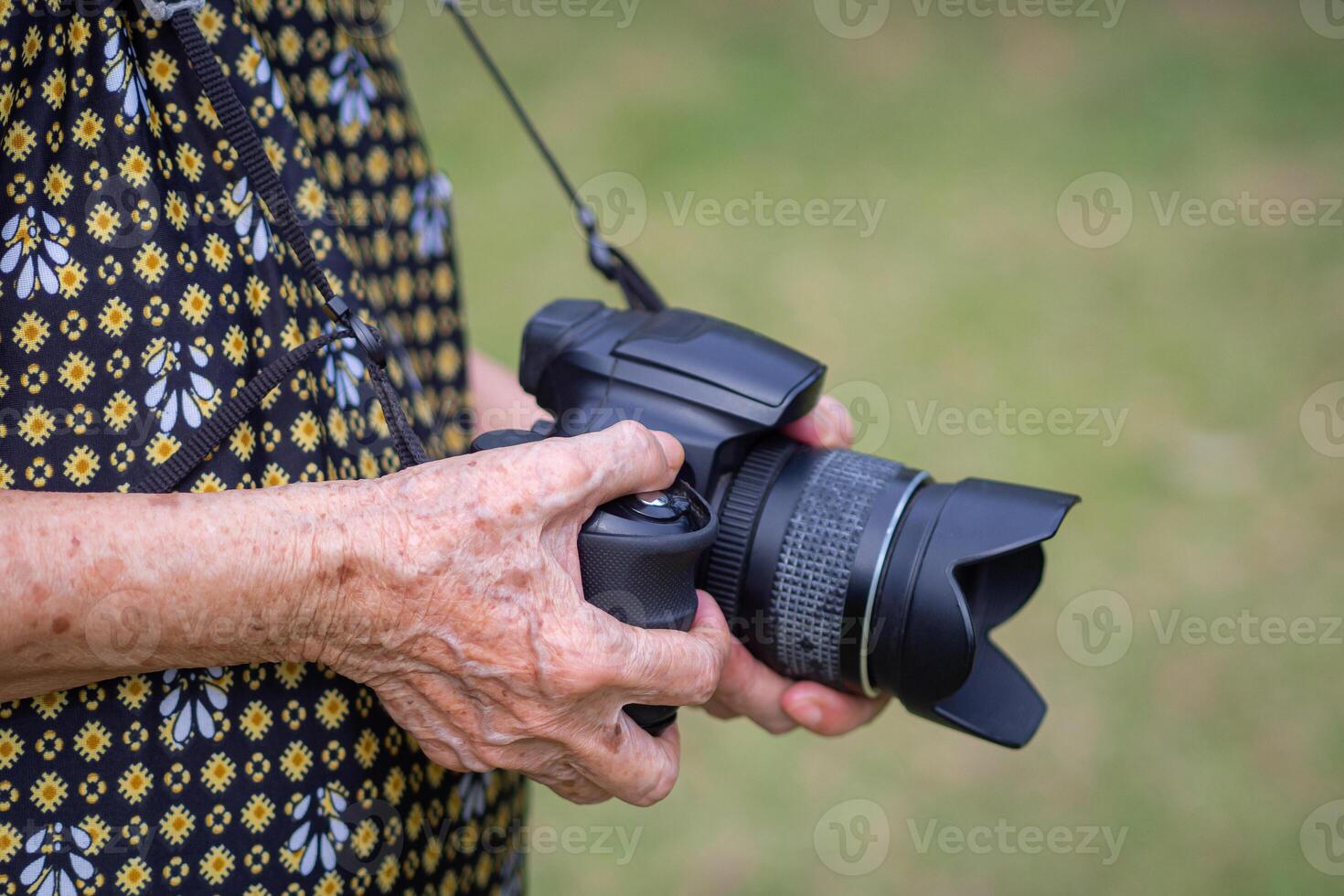 Close-up of hands senior woman holding the digital camera while standing outdoors. Concept of aged people and photography photo