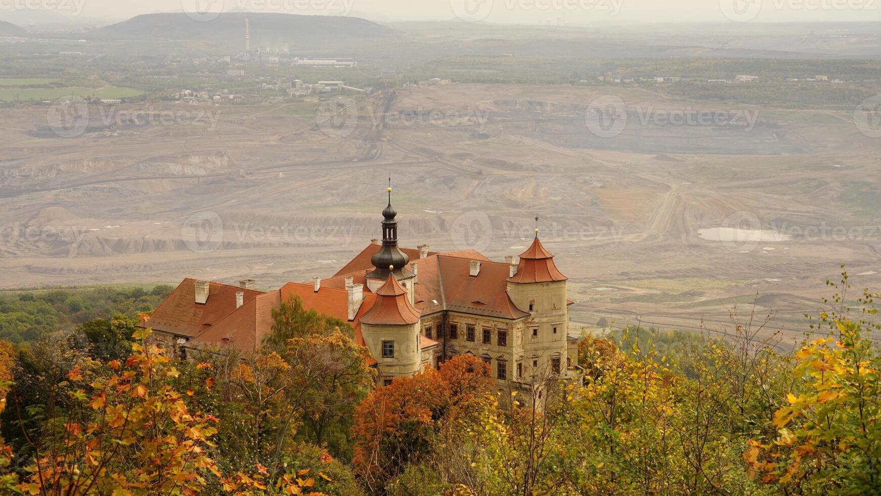 Historic castle surrounded by autumn trees with a quarry in the background photo