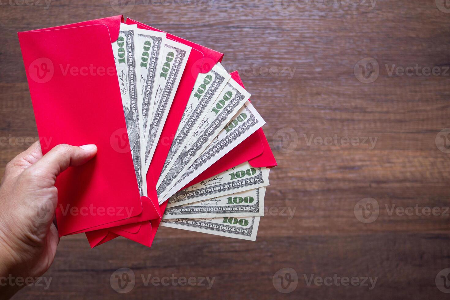 Close-up of hand holding a red envelope packet with money dollars or Ang Pao prepare for given to children during Chinese New Year for a blessing. photo