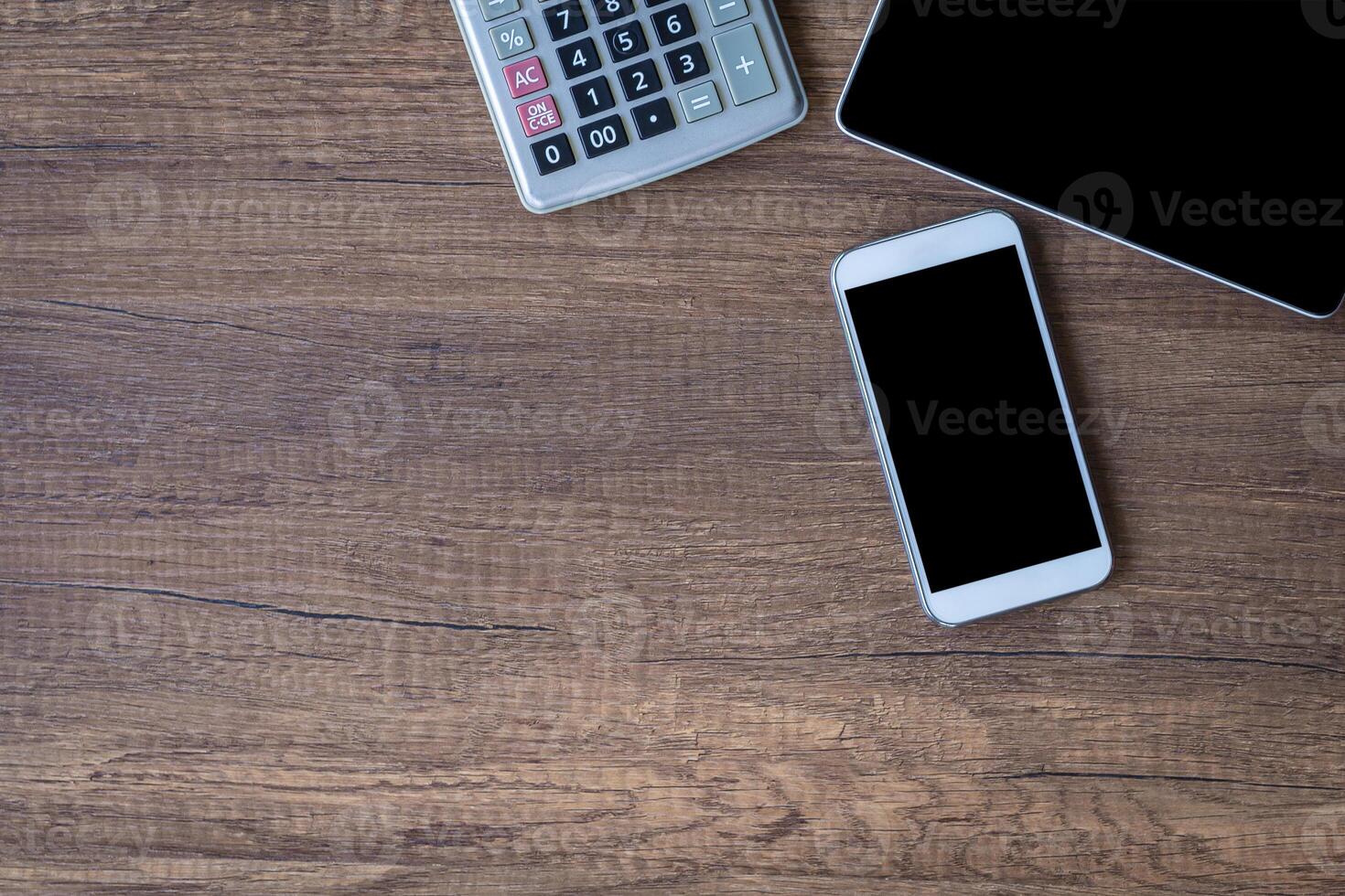Top view of a tablet, calculator, and smartphone on a wooden table. Space for text. Wood texture background. Business and technology concept photo