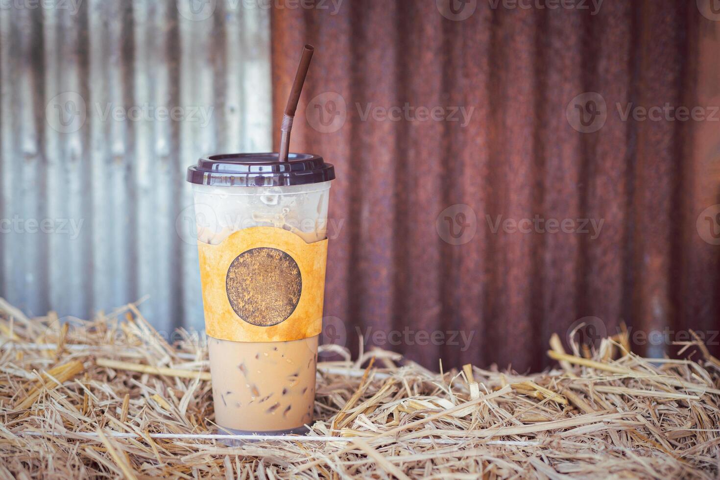 Iced coffee cup placed on a straw with a galvanized wall in the cafe shop. Space for text photo