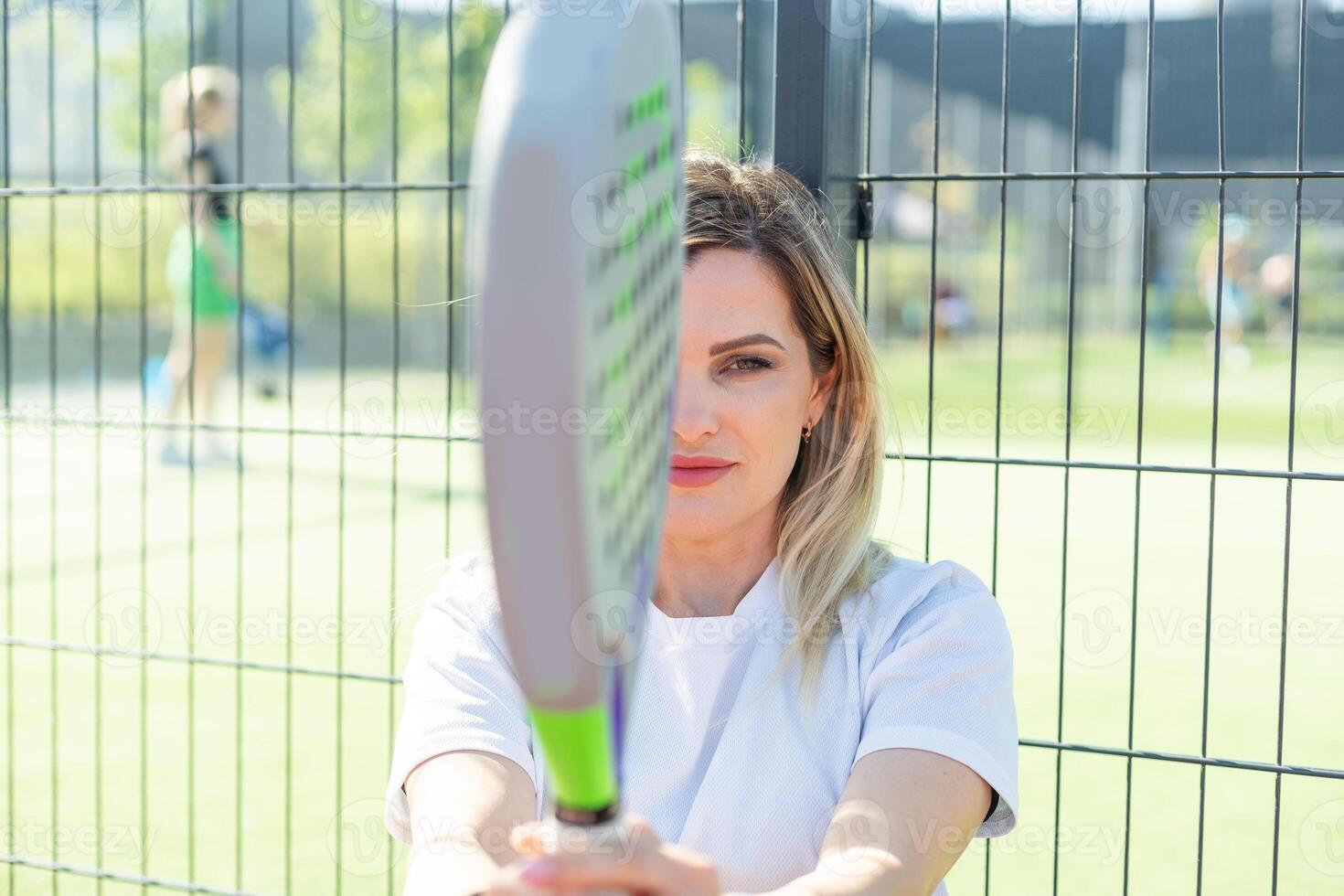 Happy female paddle tennis player during practice on outdoor court looking at camera. Copy space. photo