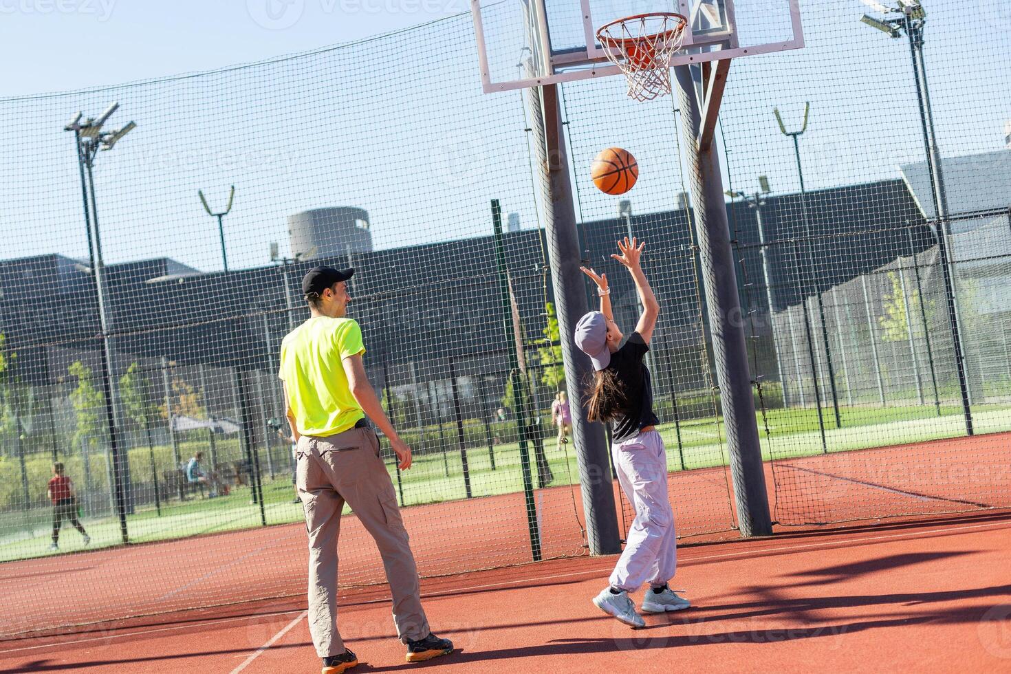 father and daughter playing basketball together on playground photo