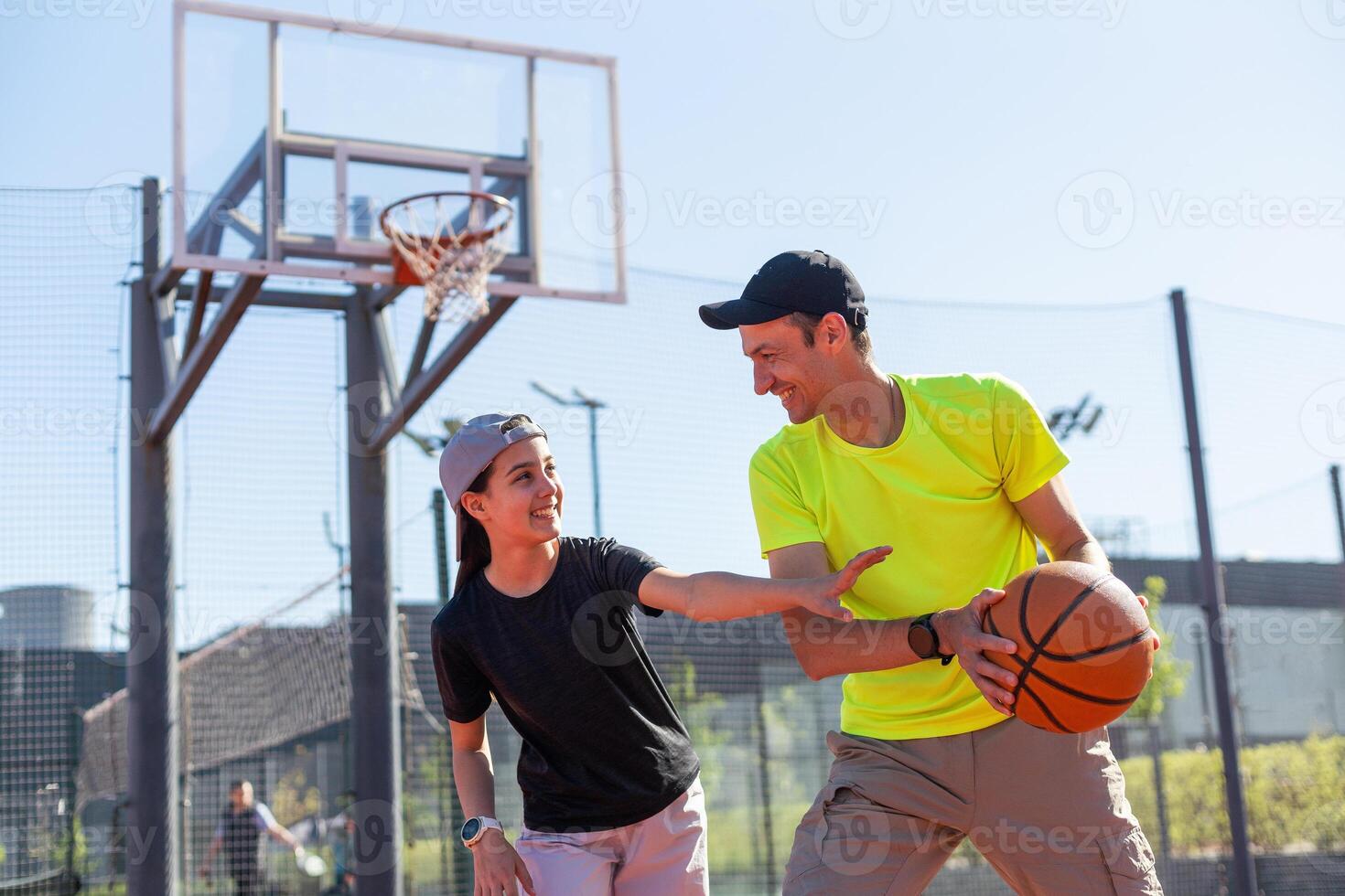 A happy father and teen daughter playing basketball outside at court. photo