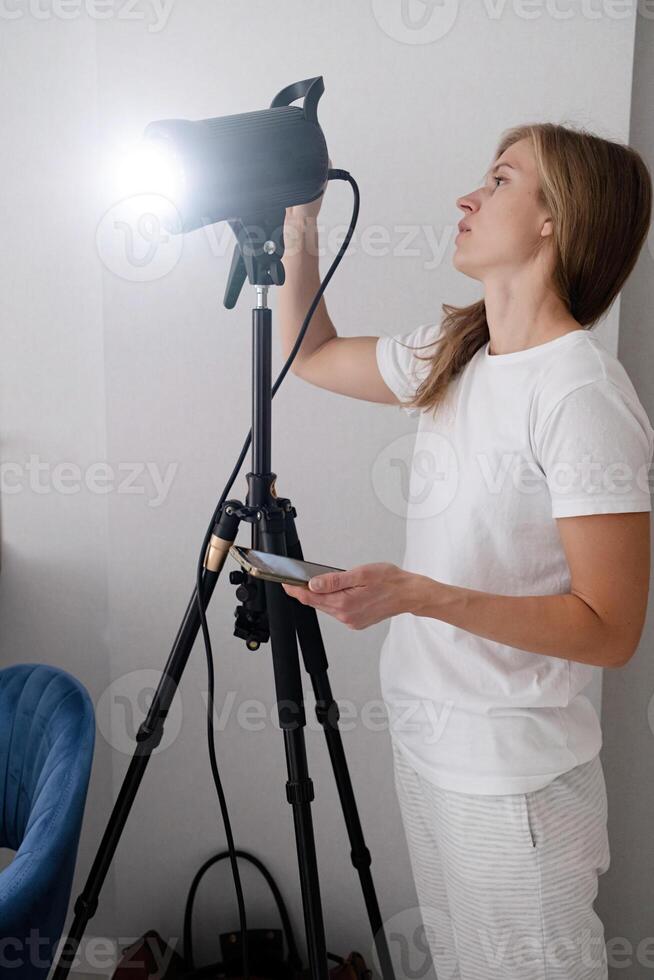 woman maker at work, working on content making, using and controlling light strobe photo