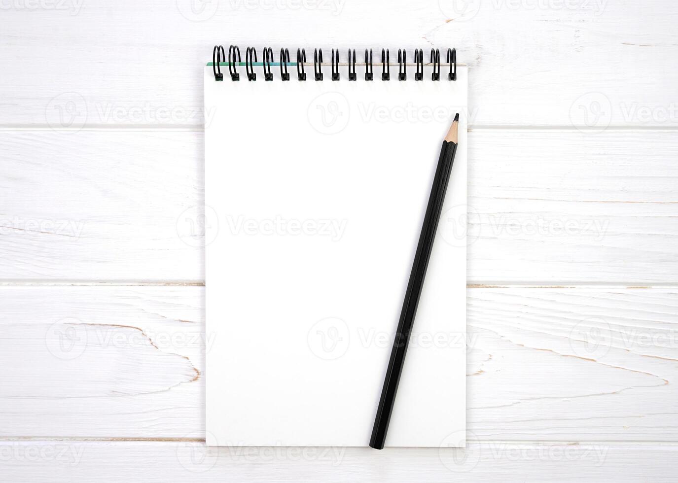 A blank notebook and a pencil on a white wooden background. Flatlay composition. Mockup. Top view. Copy space. photo