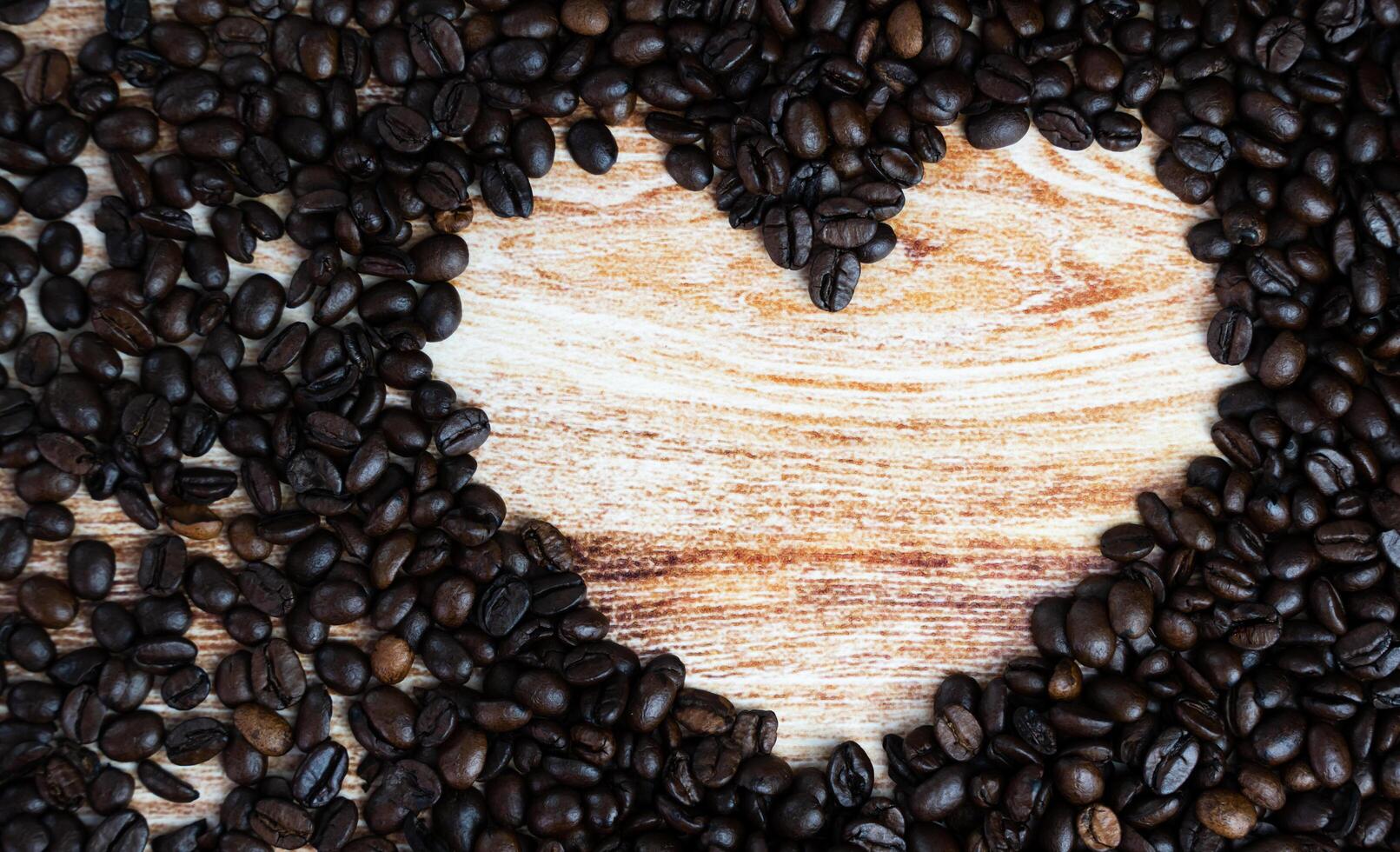 Scattered coffee beans in the shape of a heart. Coffee day. Place for text. Top view. Selective focus. photo