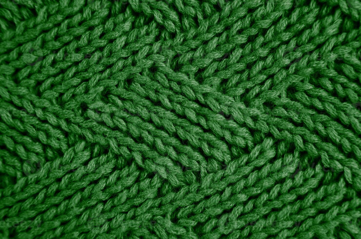 Knitted green wool scarf with a diamond pattern. Abstract background. Close-up. Selective focus. photo