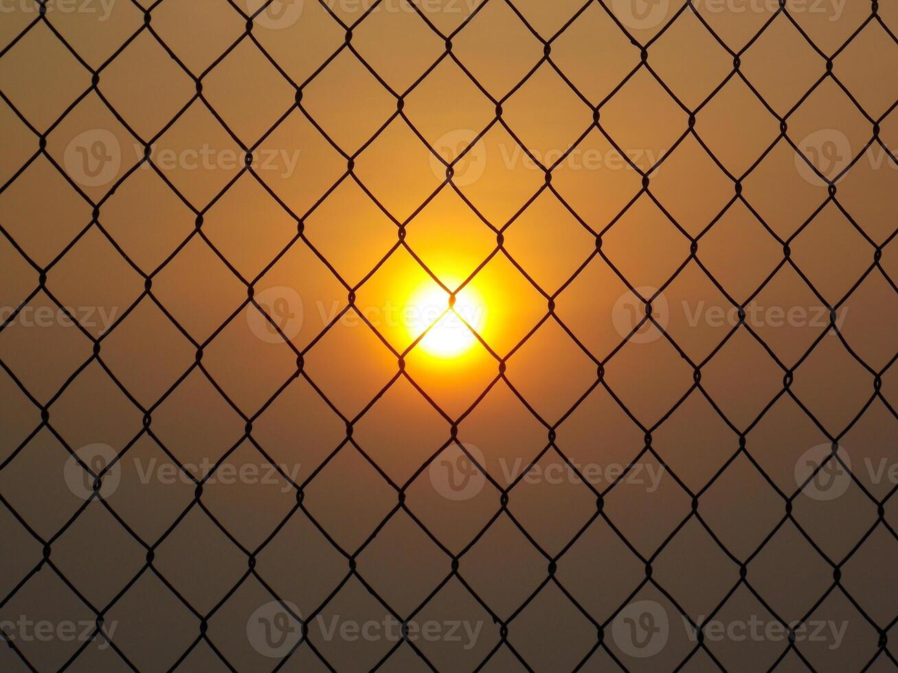 Sunset view behind chain-link fences photo