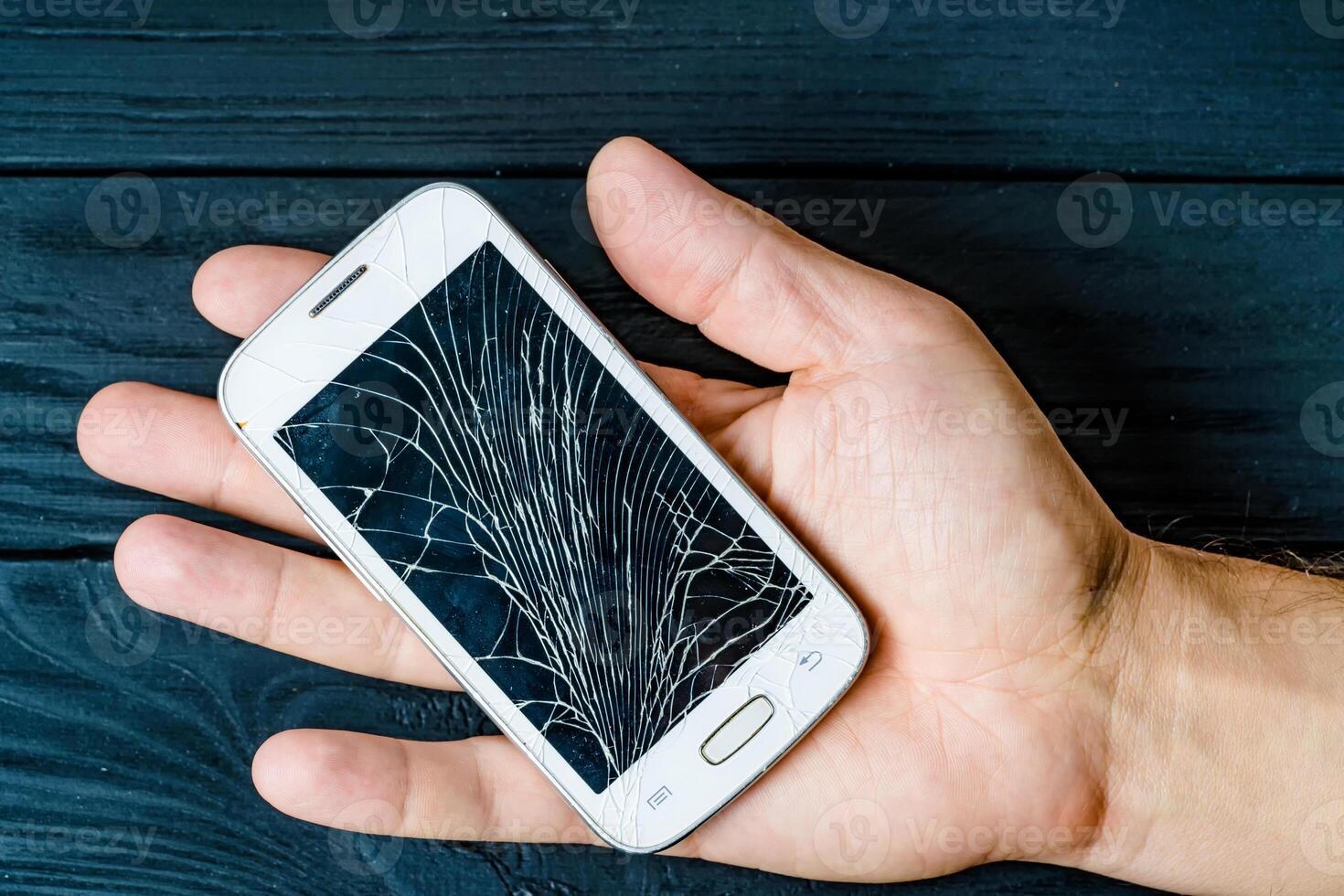 Broken cellphone holding in hands. Modern smashed electronic smartphone. photo