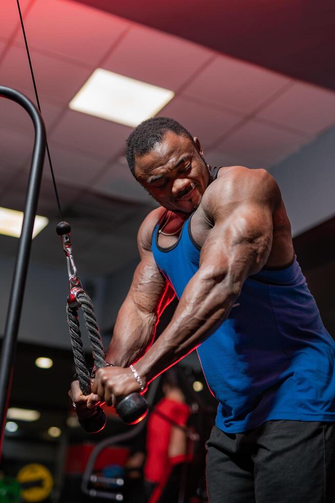 Muscular strong man working hard in the gym. Handsome sporty bodybuilder working with powerful arms. photo