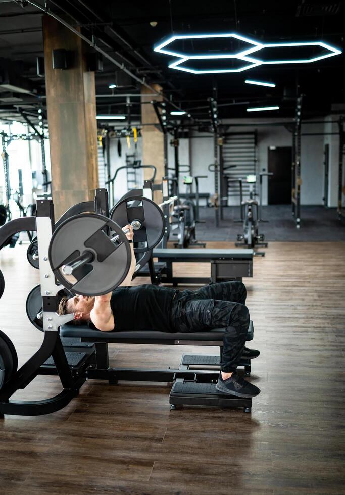 Handsome strong bodybuilder hard working in the gym. Muscular athletic man training in gym. photo