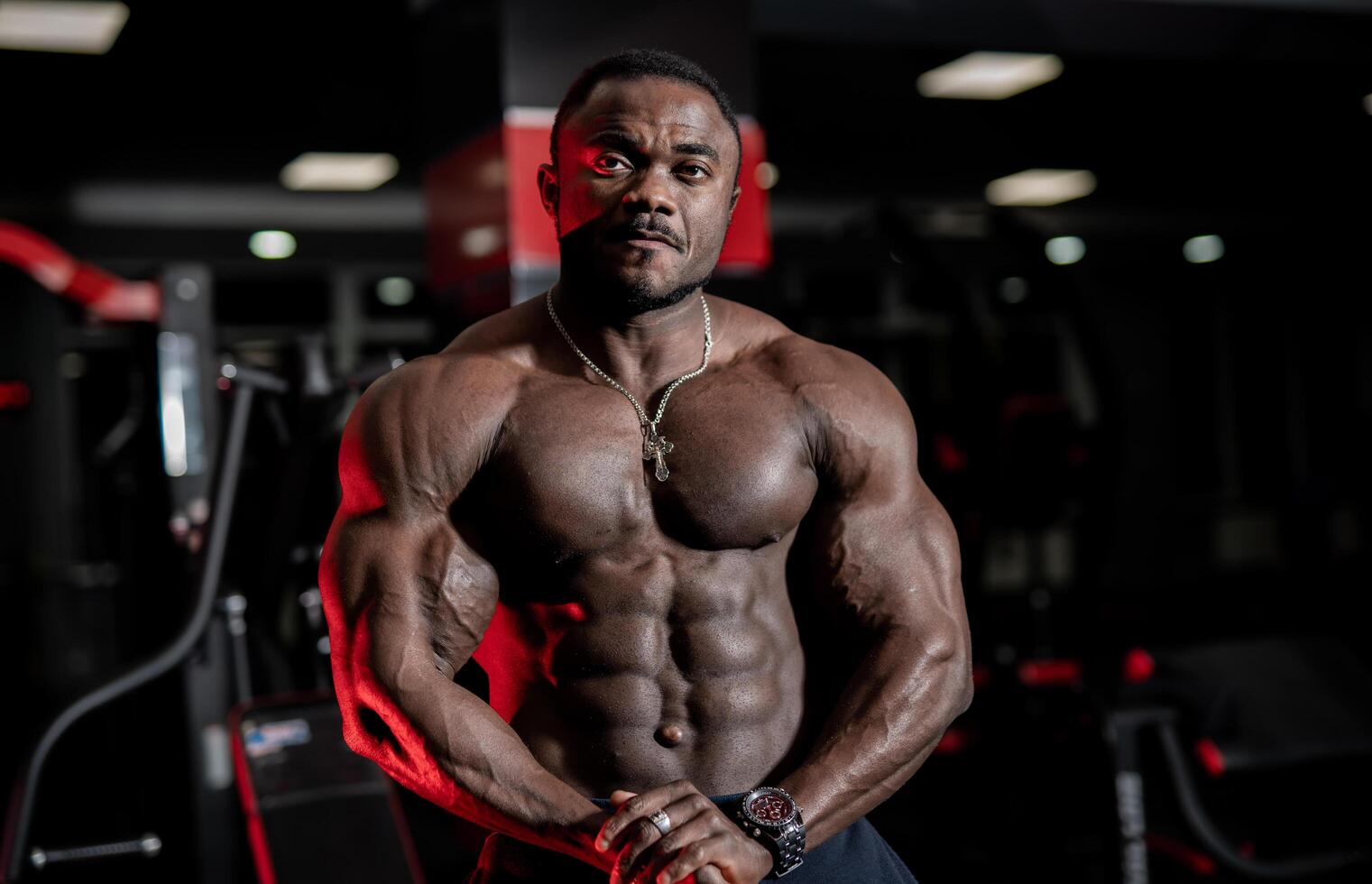 Strong handsome fitness trainer poses with modern sport gym interior on background. Naked torso with perfect muscles. Closeup. photo