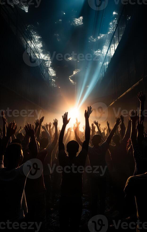 Silhouette of crowd of people dancing at concert with raised up hands and bright lights photo