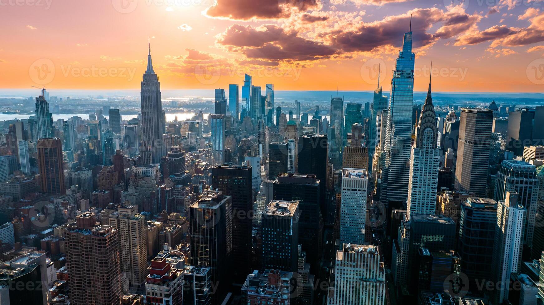 Orange light of setting sun illuminating the skyscrapers and high-rise buildings in New York scenery. Top view on the metropolis from above the East River. photo