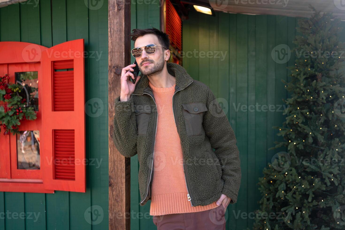 Handsome man talking on smartphone near Christmas tree photo