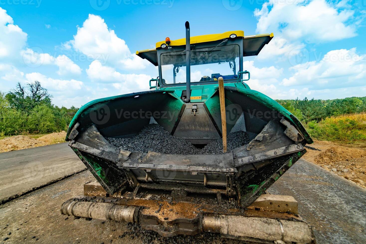 New road. Sidewalk machine paving fresh asphalt or bitumen on top of a gravel base during highway construction. photo