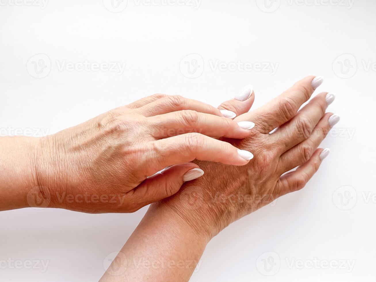 Hands middle age woman with white manicured nails gently touching each other on white background, top view. Flat lay composition. Skincare and hand care or mother love concept. photo