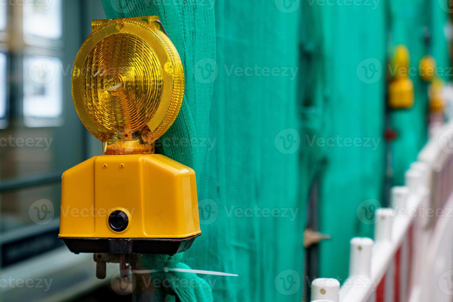 Yellow signal lamp against the background of a green fence. photo