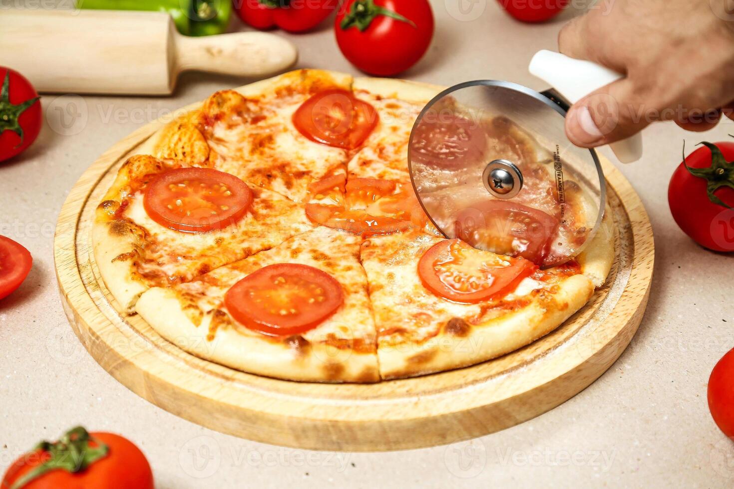 Person Cutting Pizza With Pizza Cutter photo