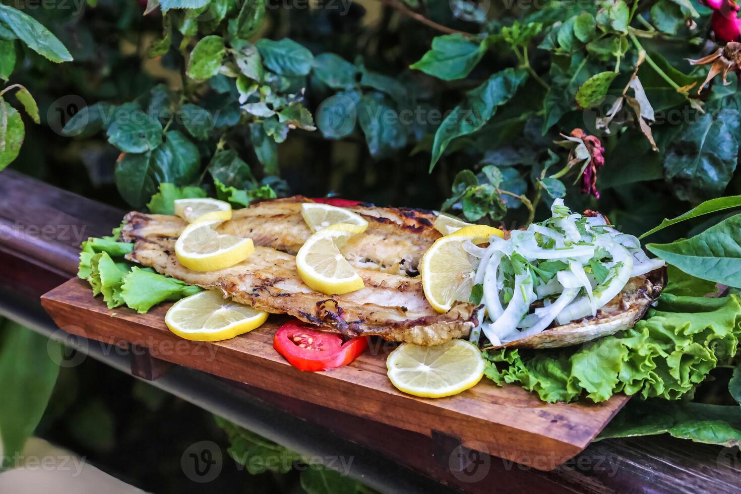 Wooden Cutting Board With Fish, Lettuce, and Lemon Slices photo