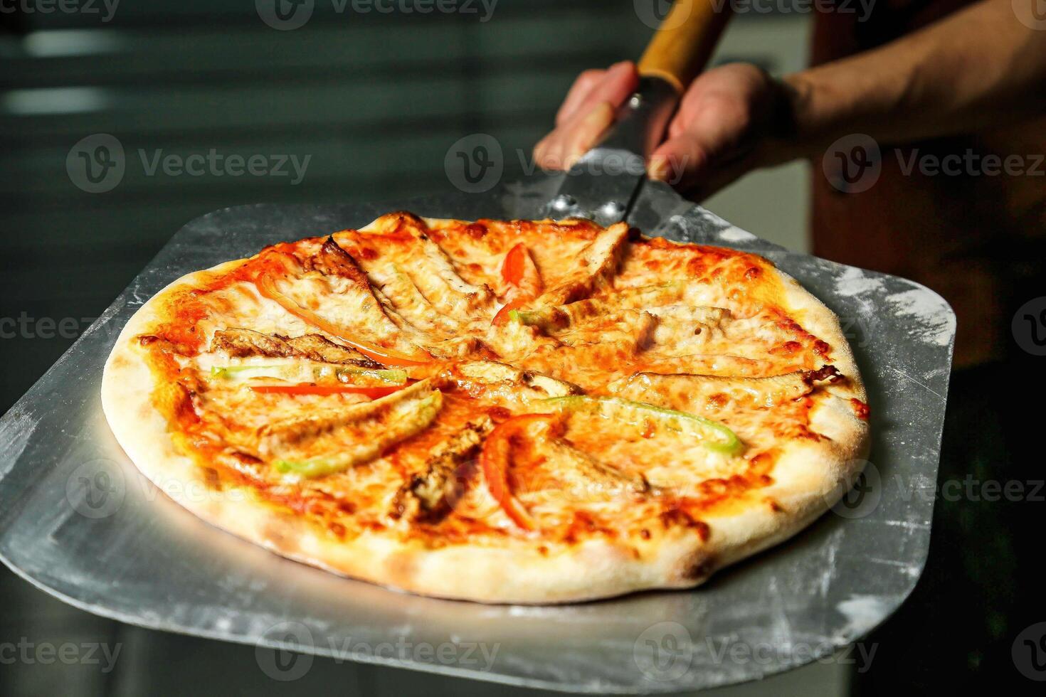 Person Cutting Pizza With Pizza Cutter photo