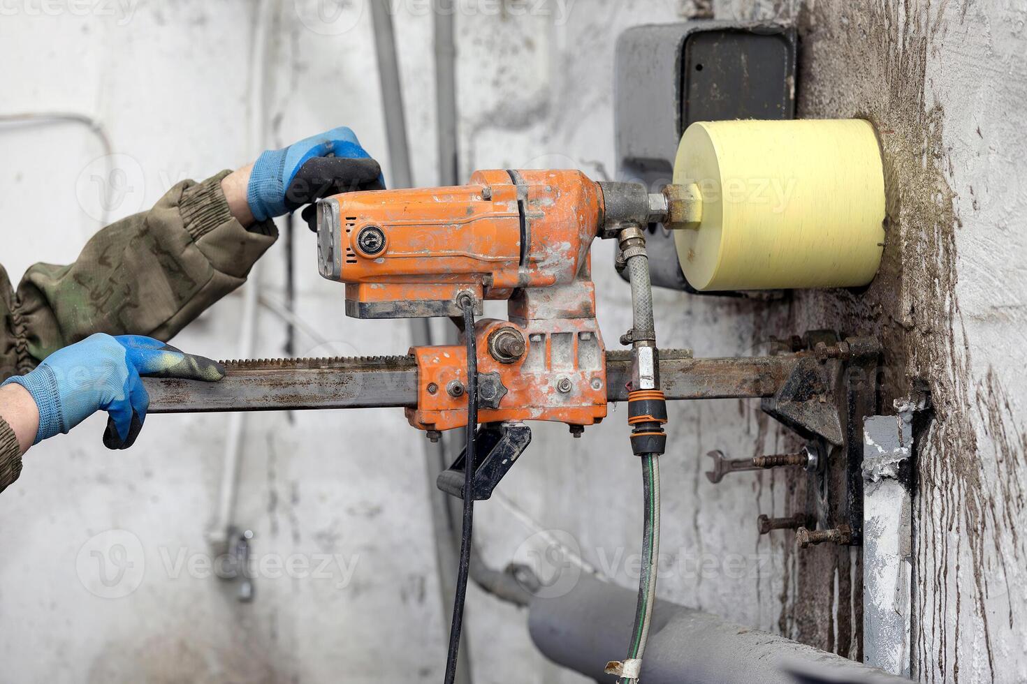 Worker using an electric drill to make a hole in a concrete wall, closeup photo