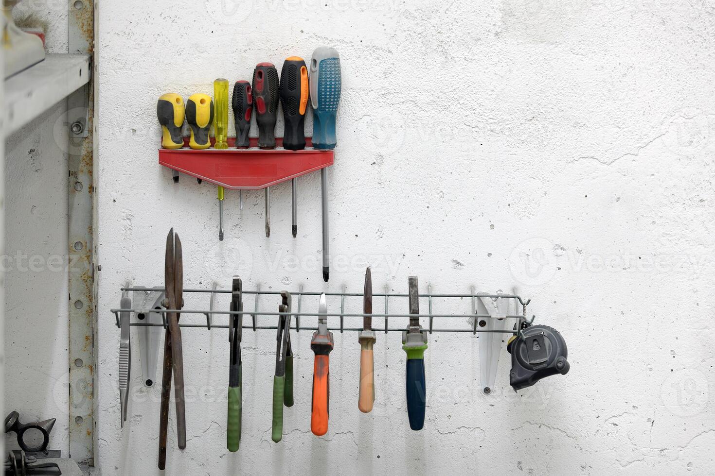 Screwdrivers and other tools hanging on a wall in a workshop photo