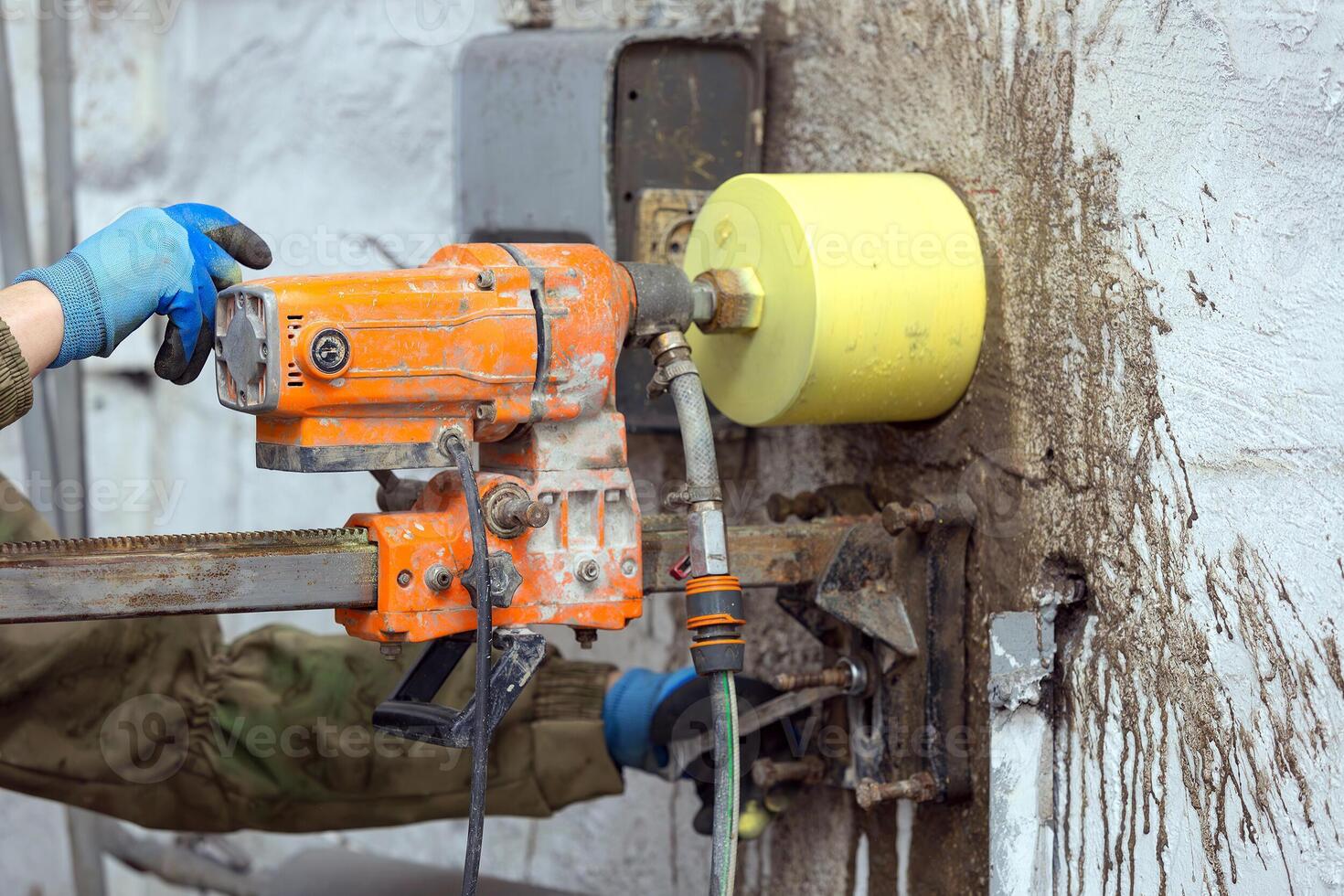 Worker using an electric drill to make a hole in a concrete wall, closeup photo