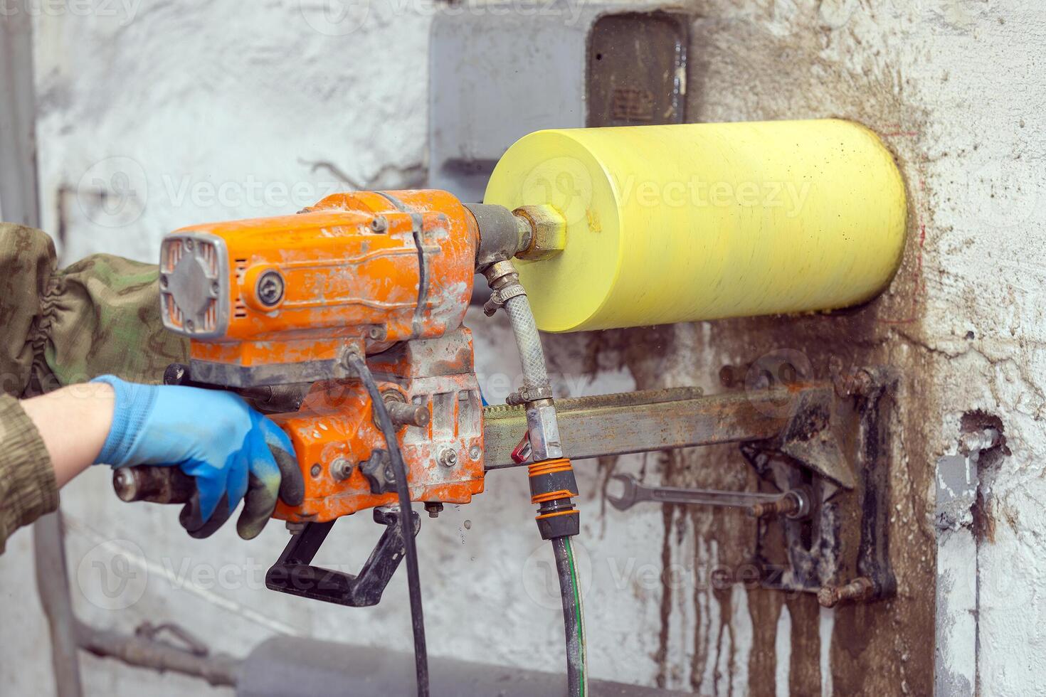 Worker using an electric drill to make a hole in a concrete wall, closeup photo
