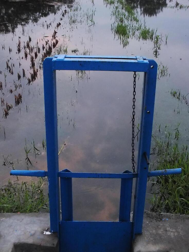irrigation channel with blue metal door for rice fields photo