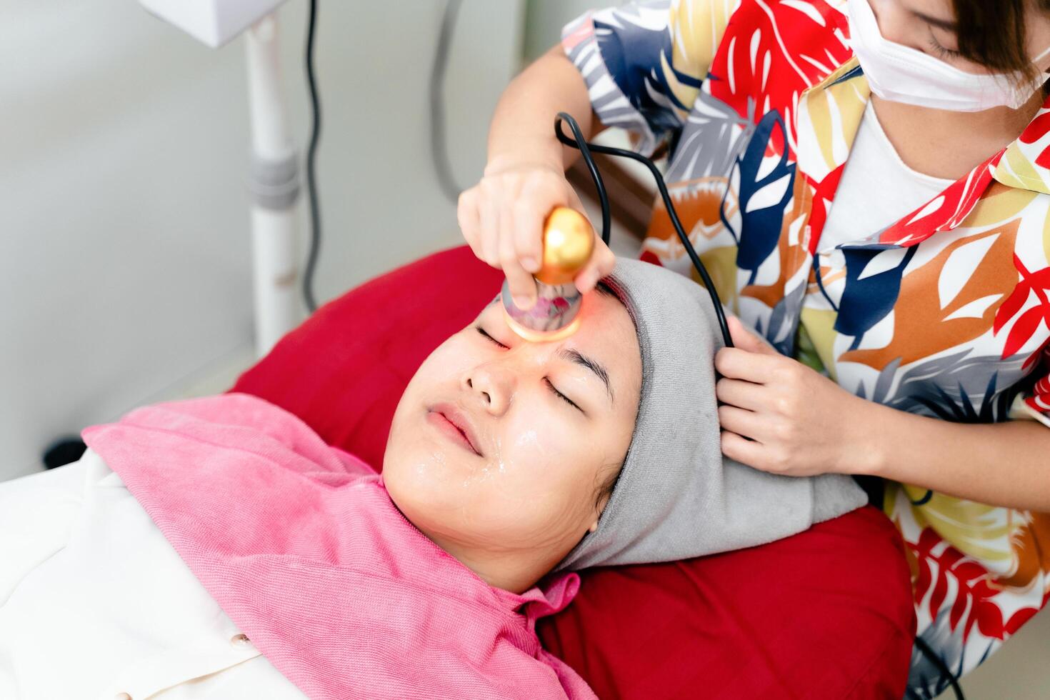 Beauticians perform ultrasound facial procedures with equipment. Woman getting facial massage. photo