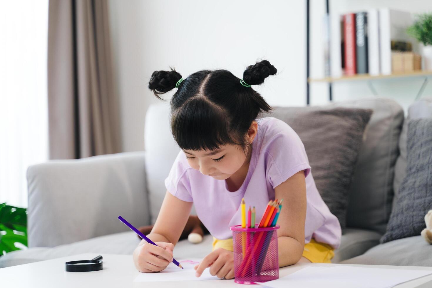 A young girl is sitting on a couch and drawing with crayons photo