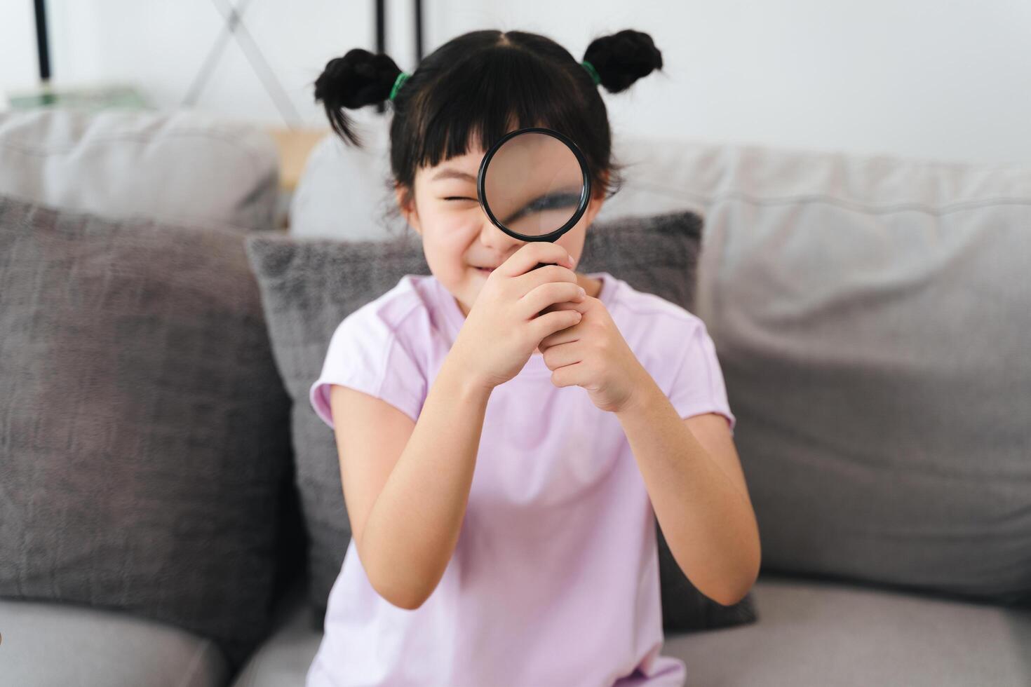 A young girl is holding a magnifying glass and looking at something photo