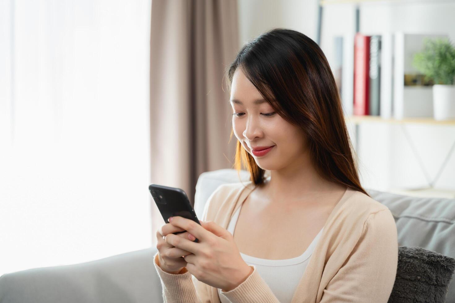 A woman is sitting on a couch and looking at her cell phone photo