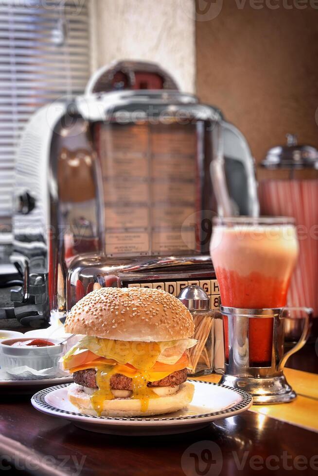 burger with cheese on plate and strawberry milkshake on old cafeteria table photo