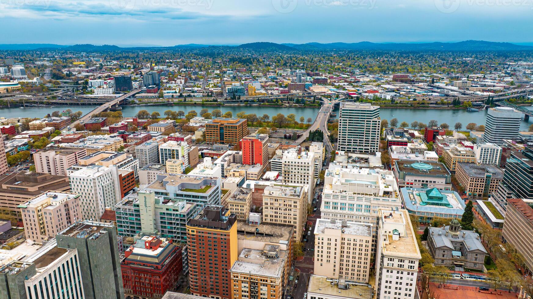 Downtown of Portland, Oregon, the USA with high-rise architecture. Twilight view of the city with mountain silhouettes at backdrop. photo