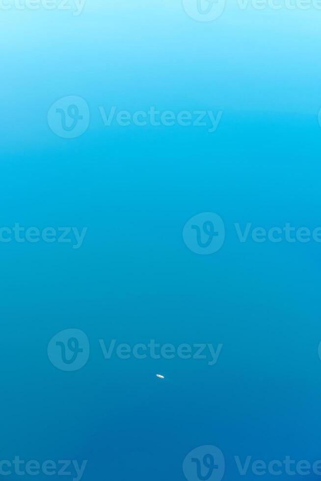 Minimal aerial view to one little cargo ship in tropical sea, beautiful light blue azure water color photo