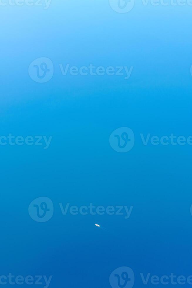 Minimal aerial view to one little cargo ship in tropical sea, beautiful light blue azure water color photo
