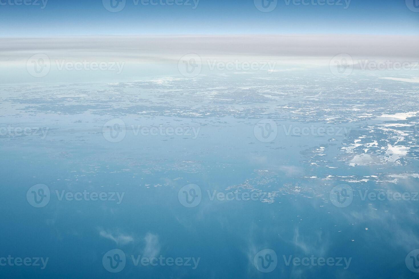 Aerial view from airplane window over clouds top to cold north sea, winter fresh frosty air photo