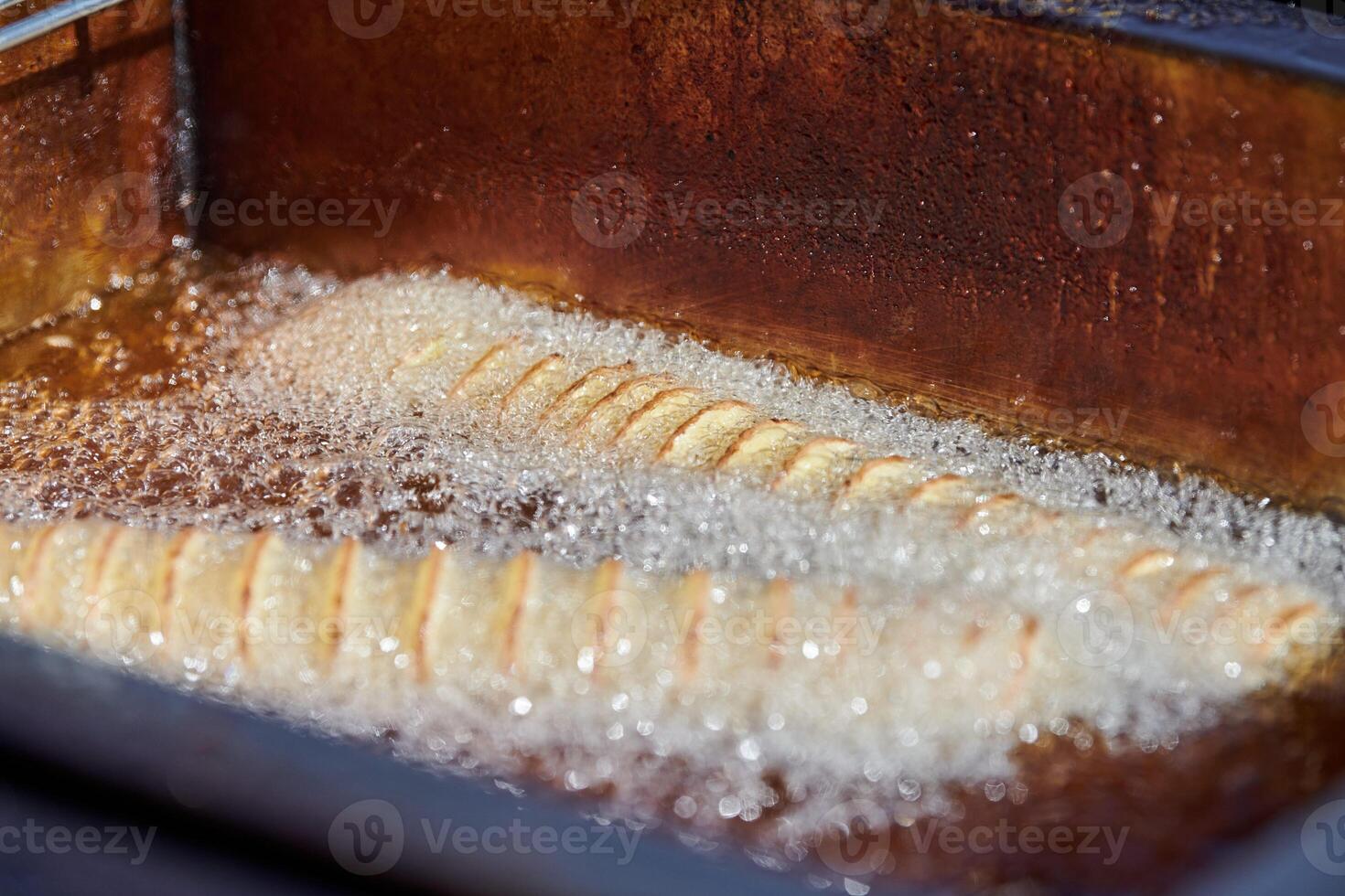 Cooking spiral fried potato in boiling oil, rich in fat and calories fast food, unhealthy delicious photo