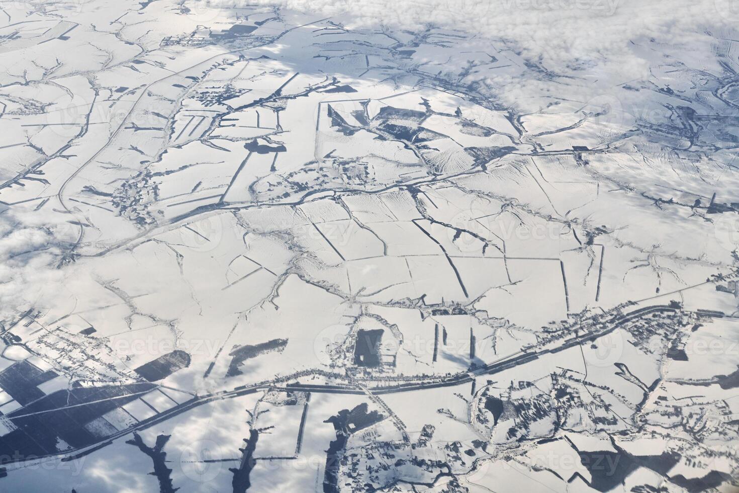 Aerial view over clouds top to snow covered rivers, fields and roads, winter fresh frosty air photo