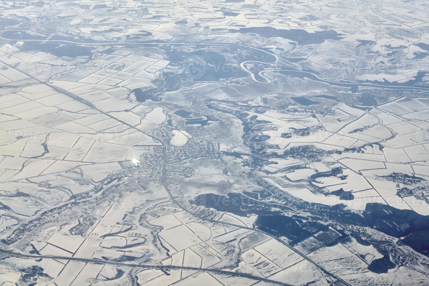 Aerial cloudscape view over clouds top to snow covered rivers, roads, cities and fields, winter air photo