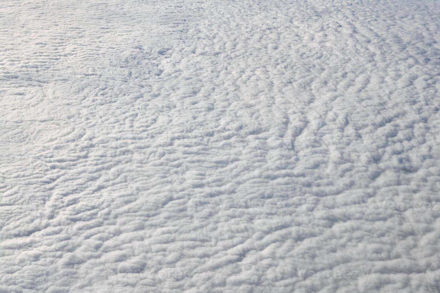 Breathtaking over clouds view from aircraft window, thick white blue clouds looks like soft foam photo