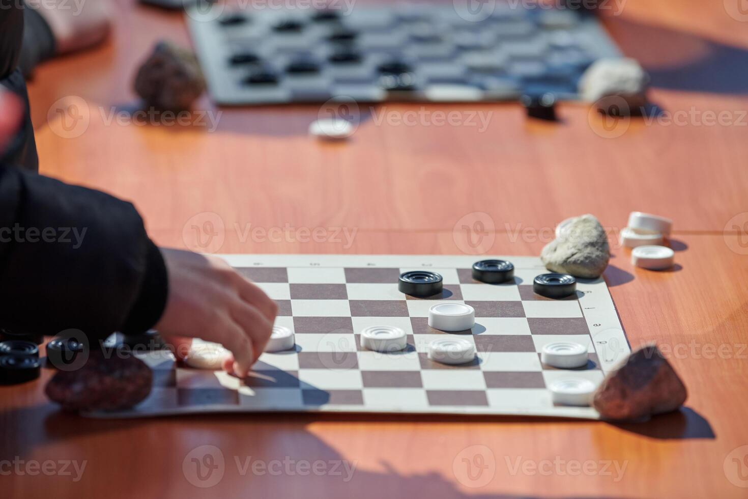 Outdoor draughts competition on paper checkerboard on table, close up players hands photo