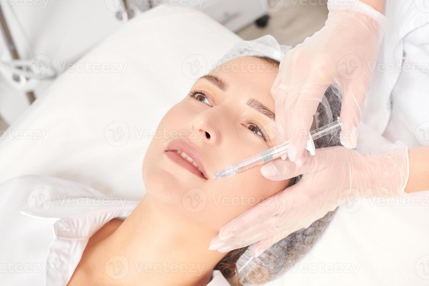 Cosmetologist makes fillers injection for lips augmentation and volume cosmetic procedure photo
