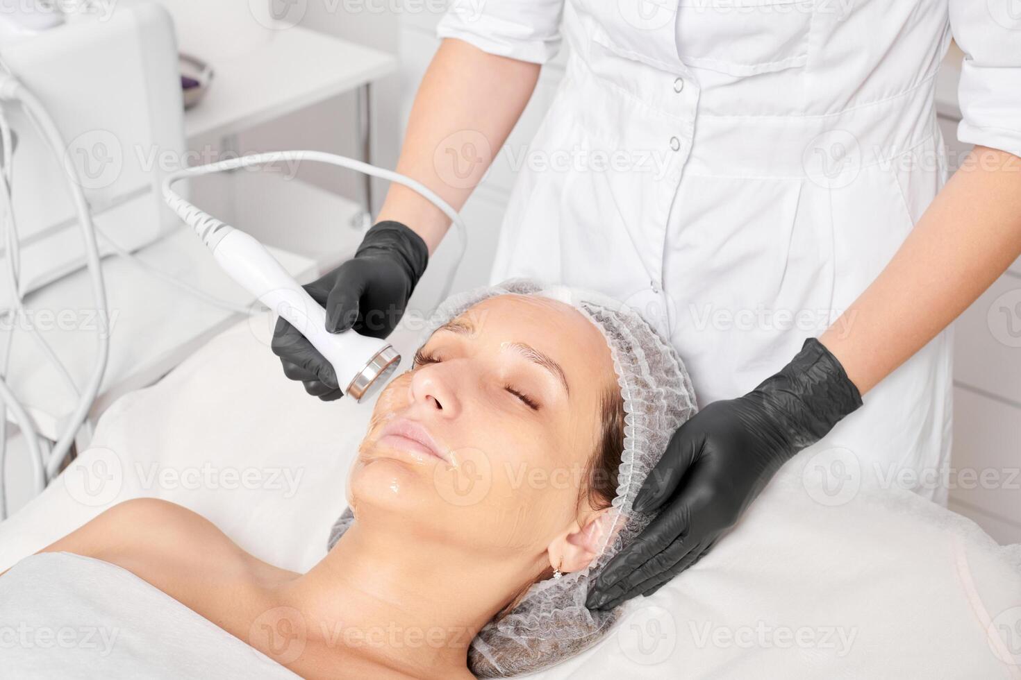 Beautician makes ultrasound skin tightening for rejuvenation woman face using phonophoresis photo