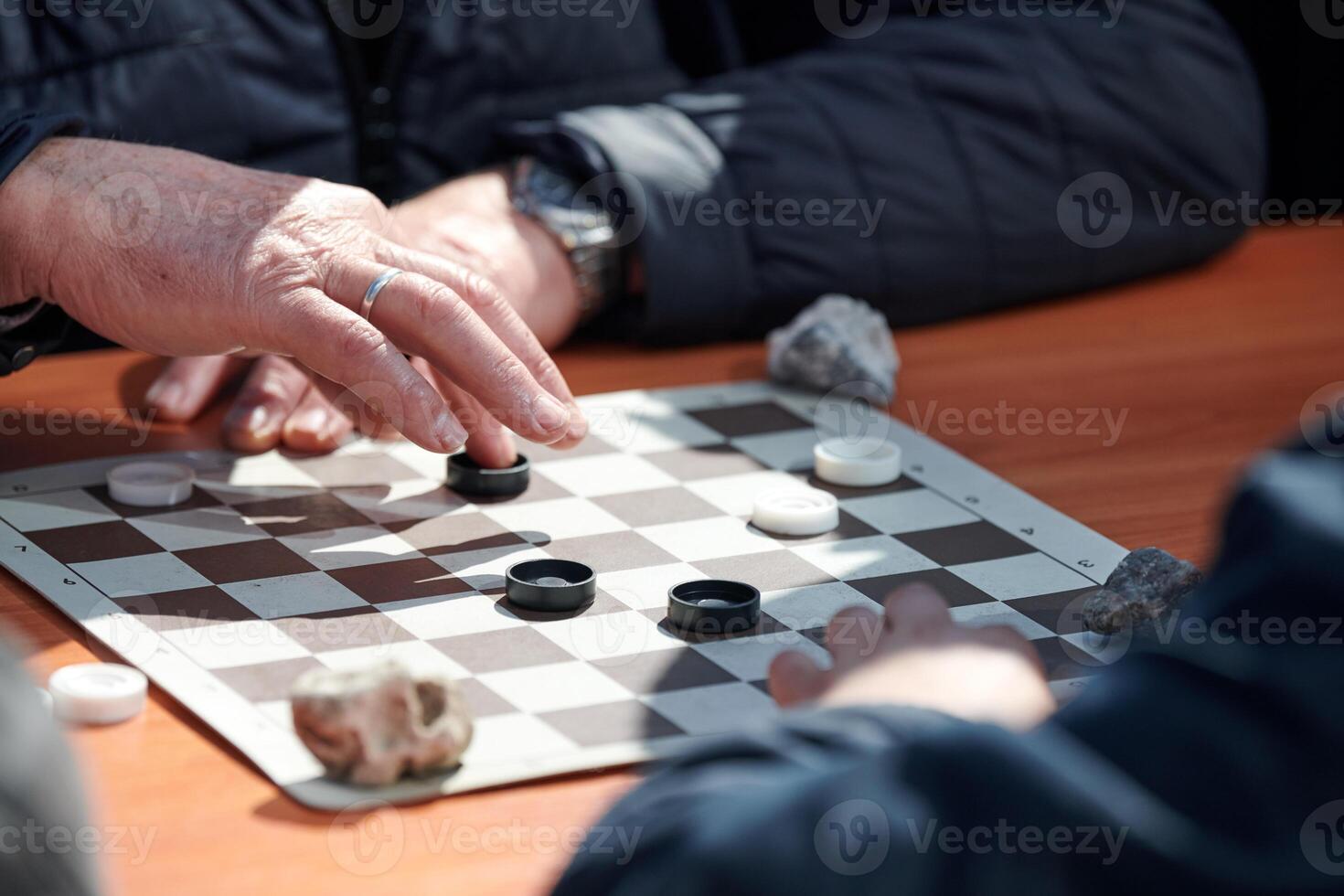 Outdoor draughts competition on paper checkerboard on table, close up players hands photo